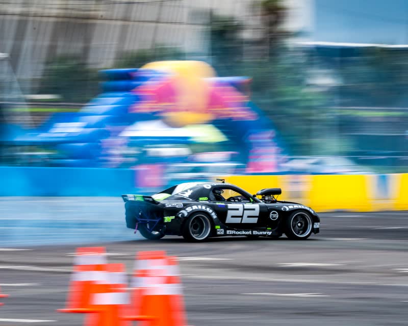 Black number 22 drift car sliding past the Red Bull arch with tyre smoke at the Red Bull Car Park Drift