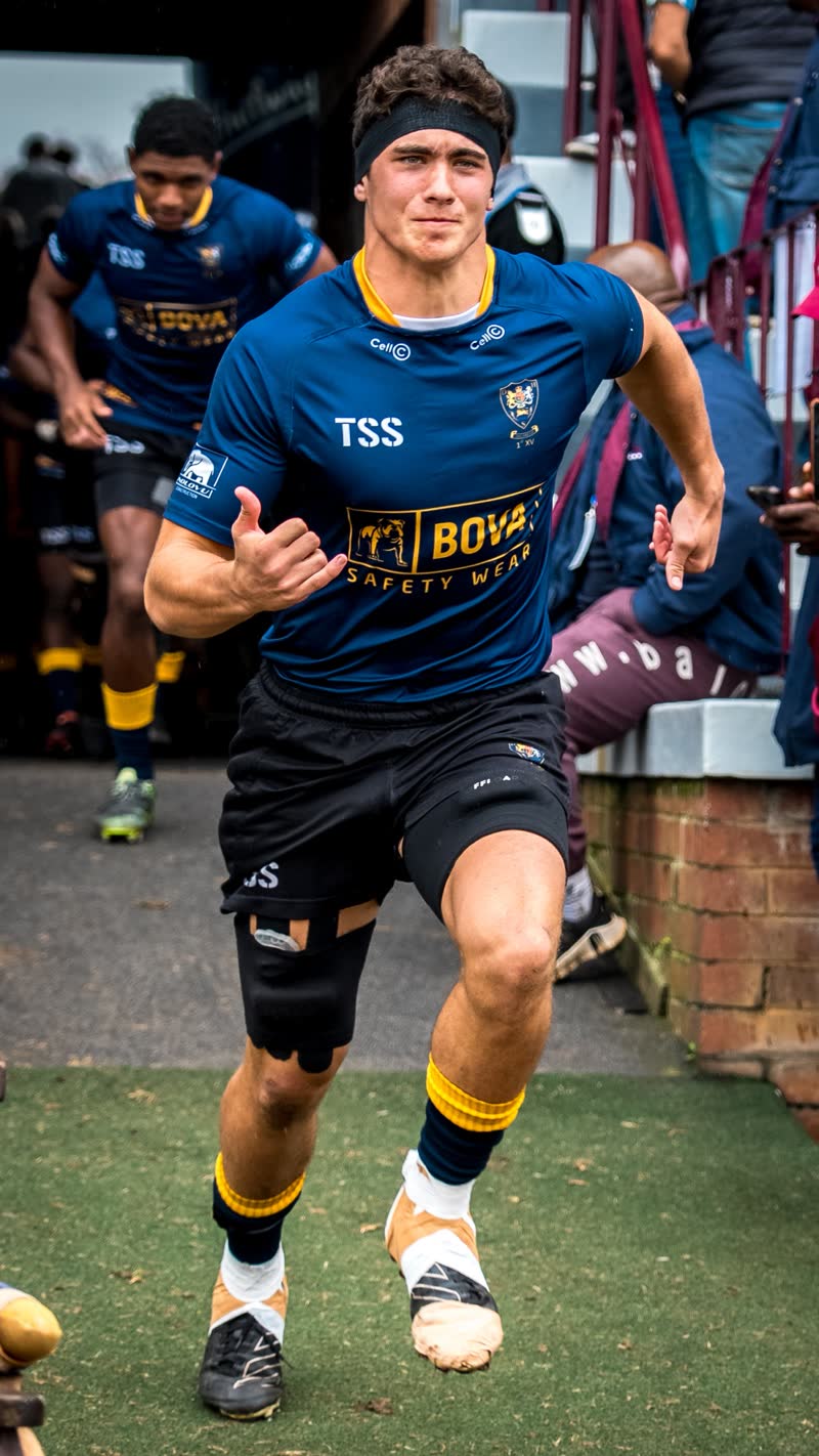 Zion Smith running out onto the field in a navy and gold first XV jersey
